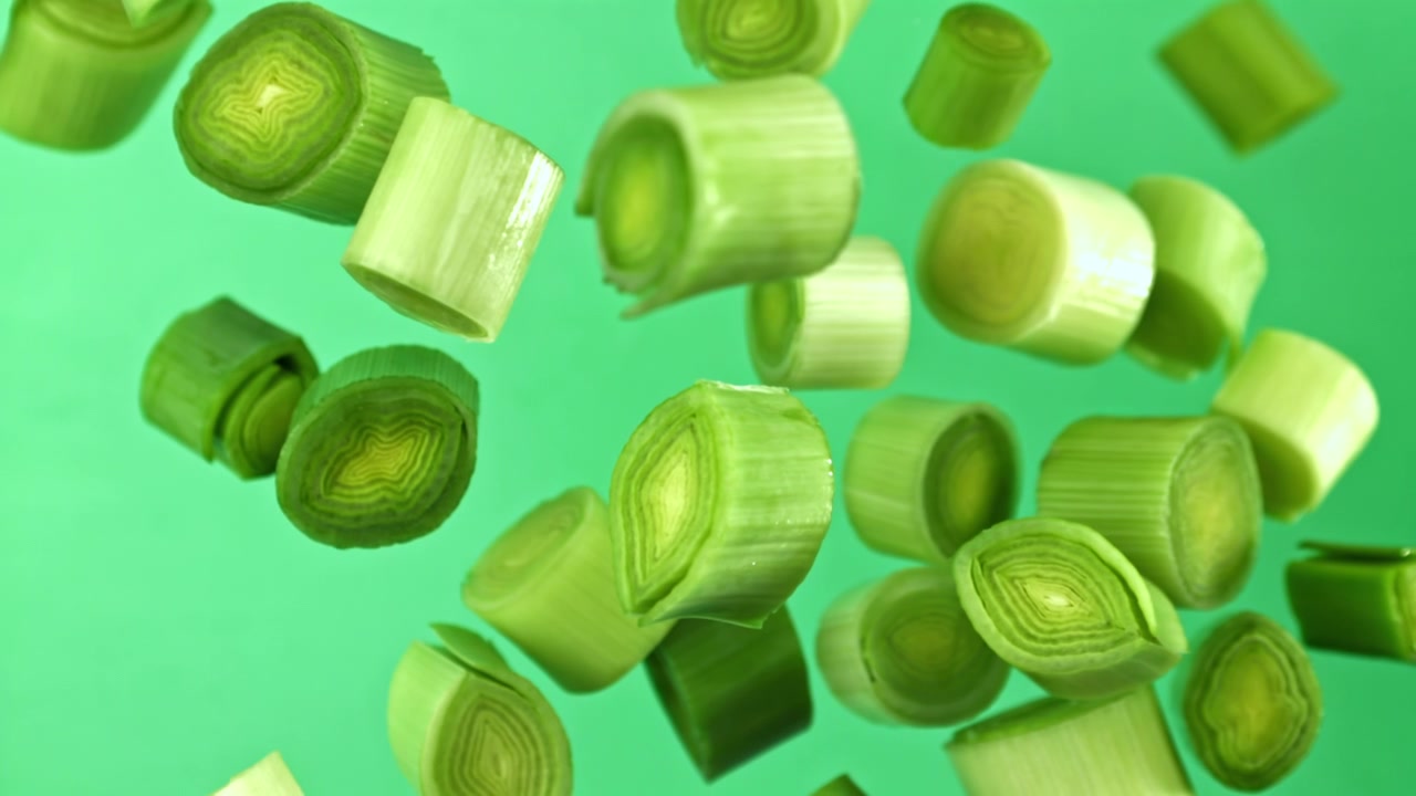 Chopped Leek Pieces Falling in Slow Motion on Green Background
