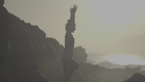 mujer practicando yoga en una playa al atardecer