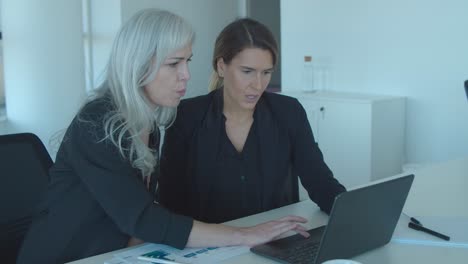 focused coworkers using laptop together