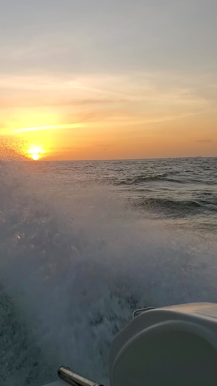 Boat speeding across the ocean at sunset