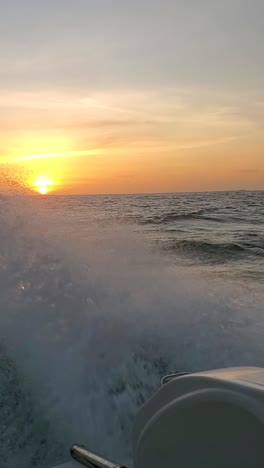 boat speeding across the ocean at sunset