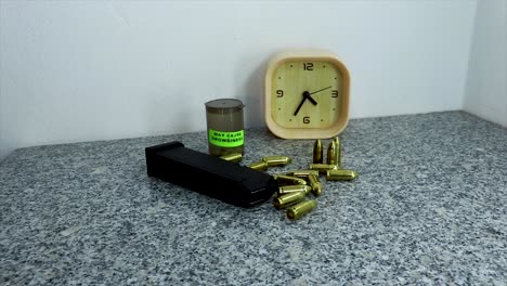 persona con guante negro coloca un arma de fuego al lado de balas reales y un cargador de armas
