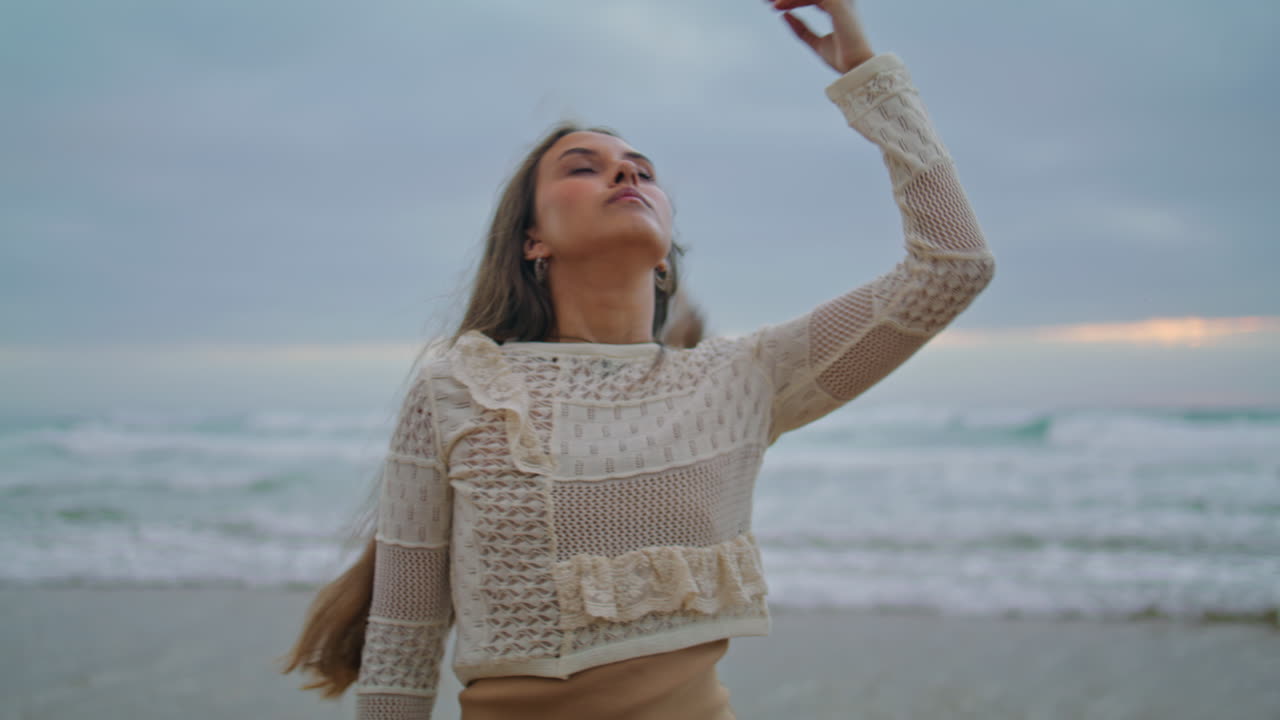 여자의 다리는 바다의 파도에 가까이 다가갑니다. 바다에서 긴 머리카락을 만지는 만적인 여성