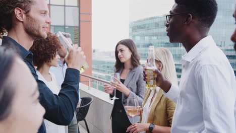 Colegas-De-Negocios-Celebrando-Con-Bebidas-En-Un-Balcón-De-La-Ciudad-Después-Del-Trabajo,-De-Cerca