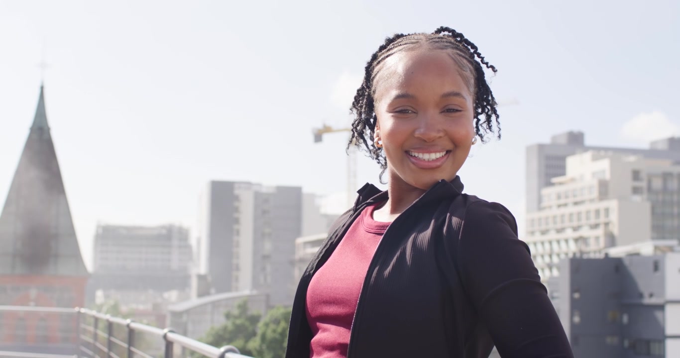 Mulher afro-americana sendo direcionada, virando-se para a câmera em um parapeito de telhado, em bordô, sorrindo