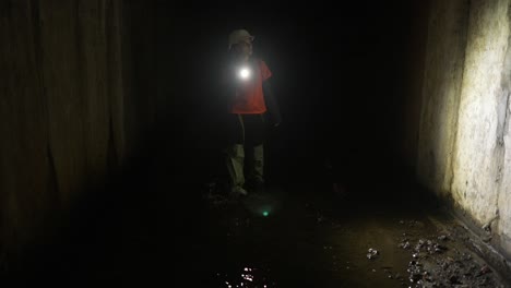 worker in a dark underground tunnel with water
