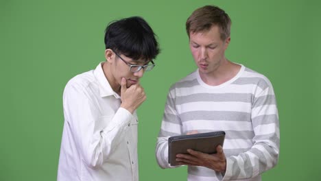 two young multi-ethnic businessmen having meeting with digital tablet together