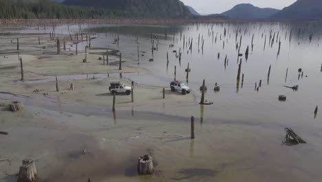 drone aerial shot of two jeeps by the water desert in no man's land in british columbia