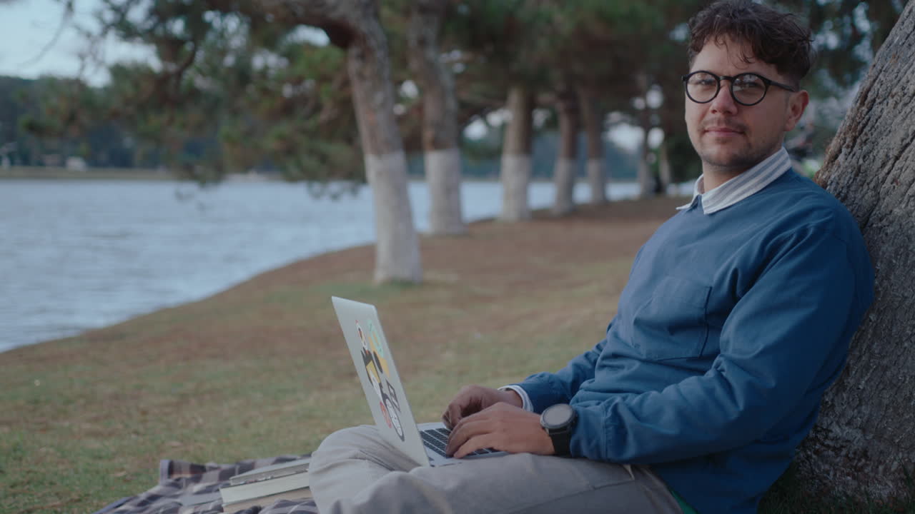 Man with Laptop Sitting by Tree Posing on Camera