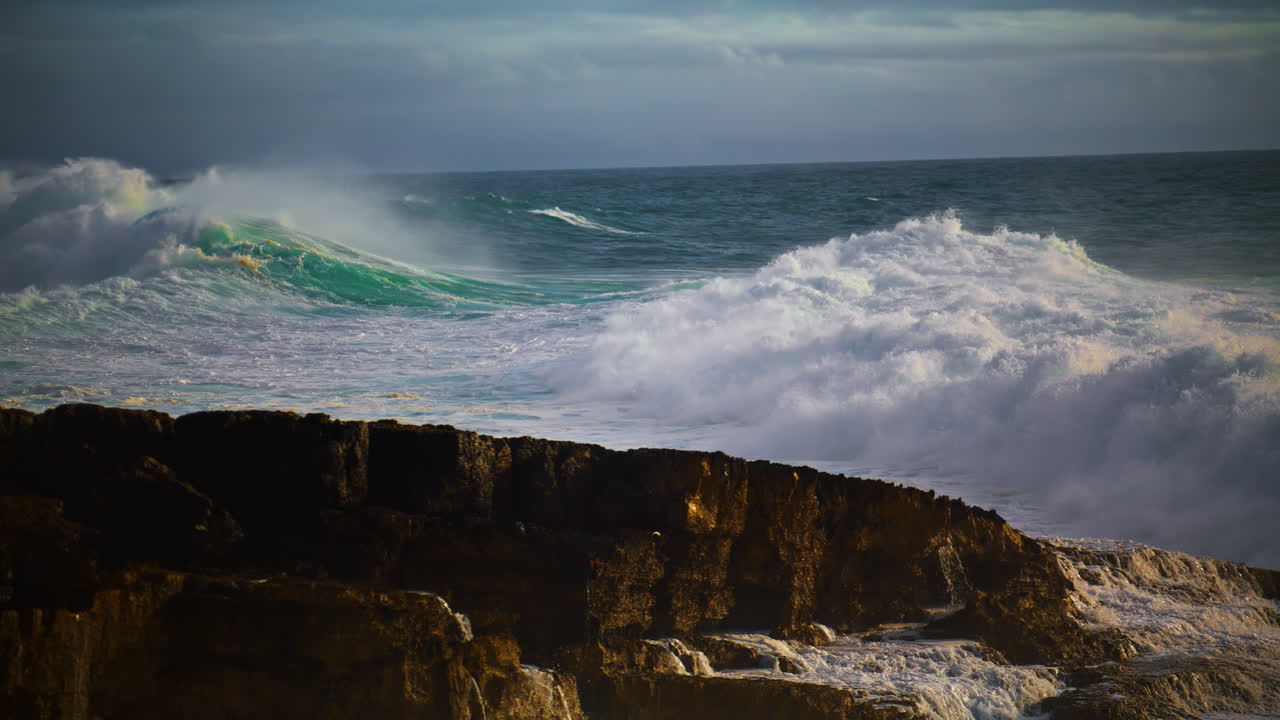 enormes olas rompiendo la playa rocosa en súper cámara lenta. poderoso oleaje de mar rodando