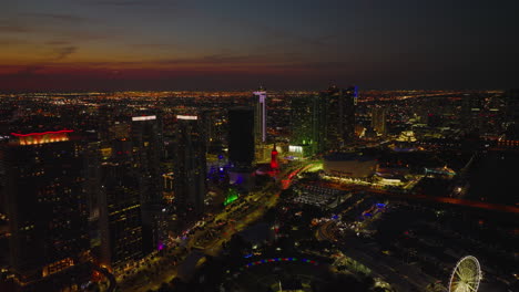 Fly-above-night-city.-Busy-streets-around-modern-high-rise-apartment-buildings-and-large-residential-boroughs-in-flat-landscape.-Miami,-USA