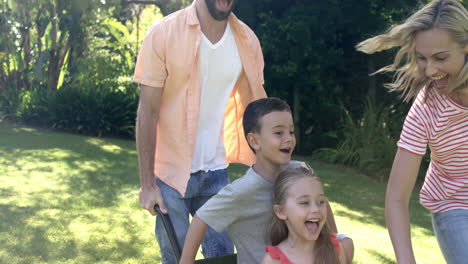 portrait of cute family playing with the wheelbarrow in the garden