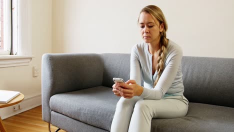 Mujer-Usando-Teléfono-Móvil-En-El-Sofá-De-La-Sala-De-Estar