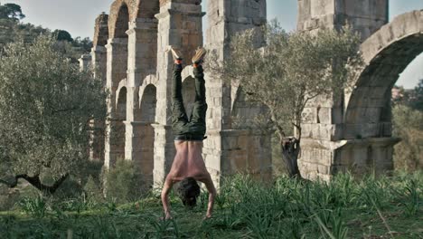 un joven en forma hace una prensa de pie al aire libre frente al antiguo acueducto