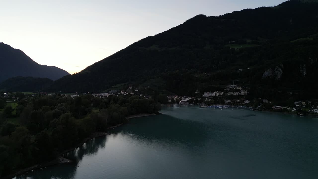 una vista serena de drones de las montañas oscuras sobre el lago walensee, suiza, temprano en la mañana.
