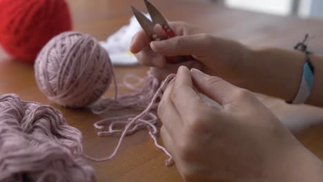 Medium-view-of-hands-holding-and-trimming-yarn-with-flat-sewing-scissors