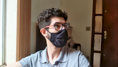 young latin man with undercut haircut uses webcam and reflects near the window at home wearing mascara on his face