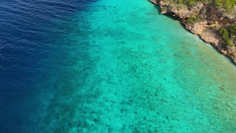 Aerial-top-down-of-ocean-drop-off-from-overhanging-tropical-cliff