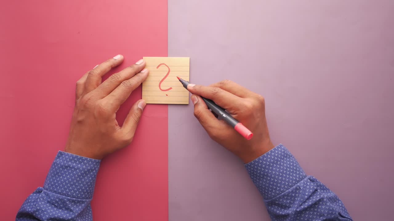 vista de alto ángulo de la escritura de un signo de pregunta en una nota adhesiva