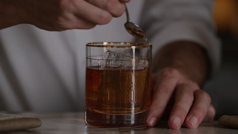 bartender sprinkles gold sugar onto an old fashioned for a garnish