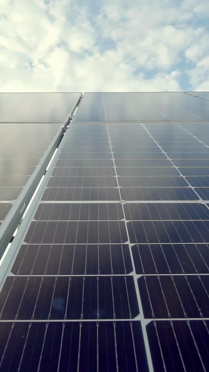Close-up view of solar panels capturing sunlight under a partly cloudy sky, vertical