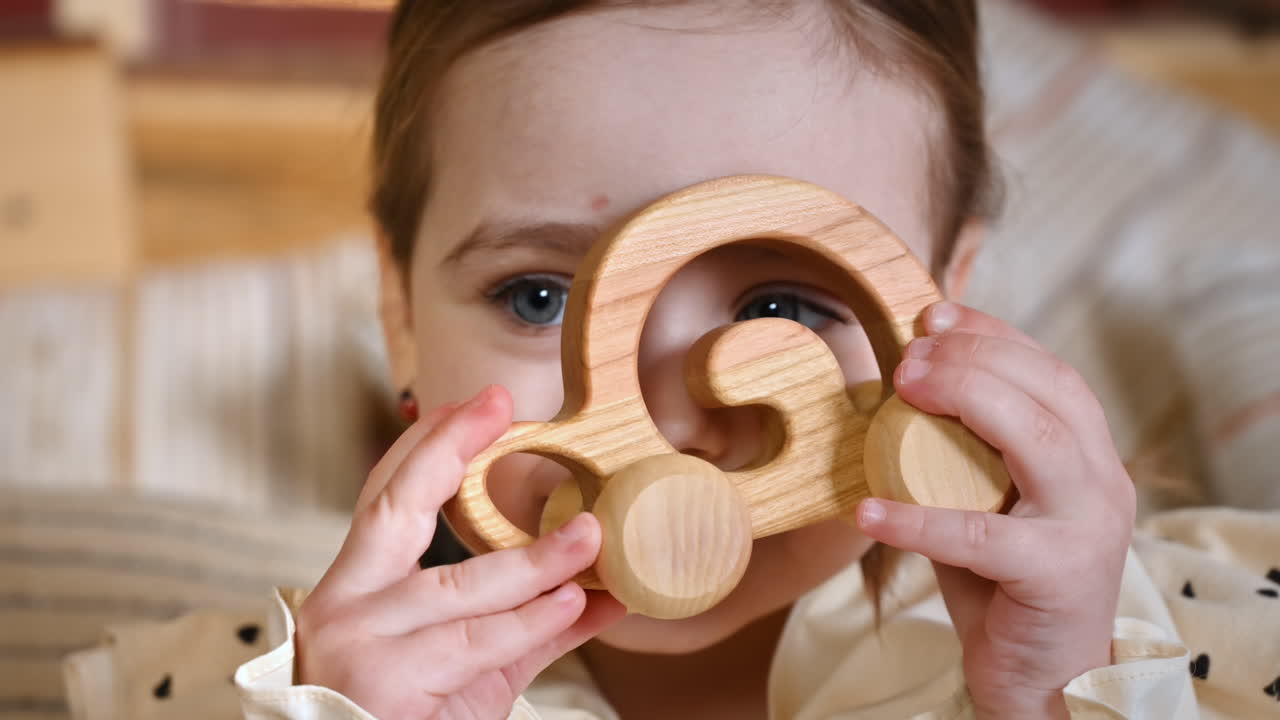 Little girl with blue eyes holding a wooden snail rolling toy. Ecological and sustainability concept