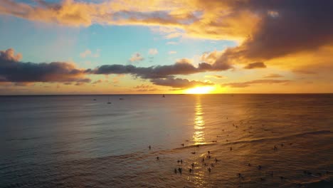 drone view, radical surfers catching sets of waves at sunset on famous waikiki beach, dawn patrol hang ten with tourists and colorful sky in honolulu, hawaii