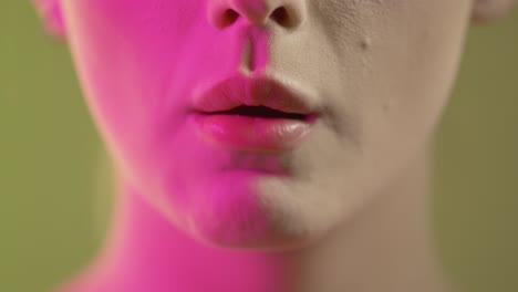 close up of woman's face and mouth, eating and chewing wafer, colorful studio lighting