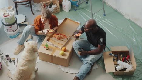 couple eating pizza and feeding dog on break during home renovation