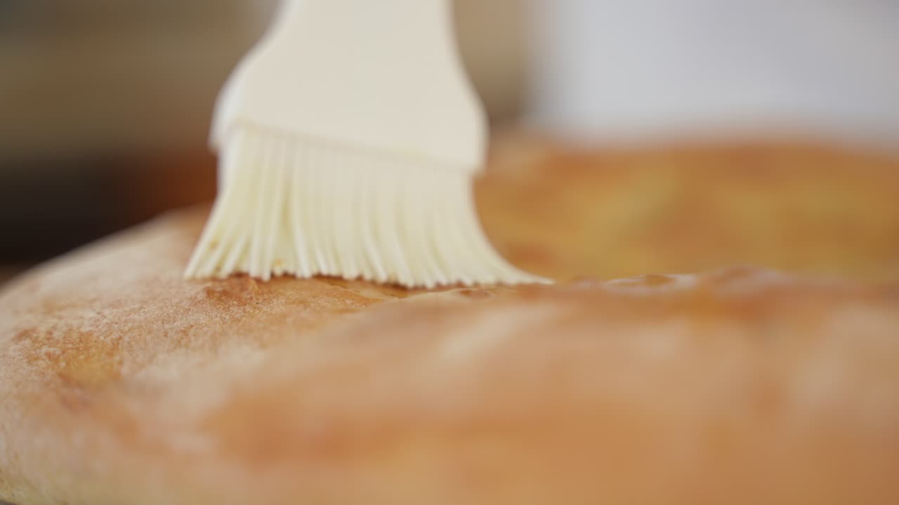 Pizzakruste mit Öl bepinseln (weiße Bürste), selektiver Fokus, Textfreiraum.