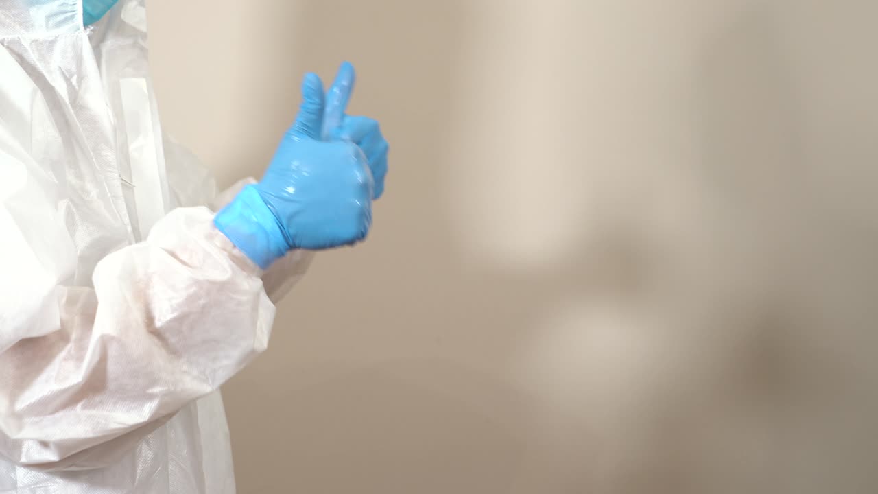 two doctors in ppe suits cleaning their hands with disinfectant gel