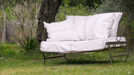 in the midst of the green courtyard, a sofa with white cushions stands, inviting relaxation and comfort