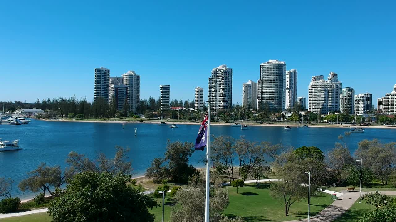 toma panorámica de una bandera alta ondeando con una fuerte brisa cerca de una ciudad importante.