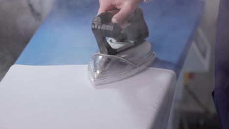 female hand ironing clothes at laundry shop