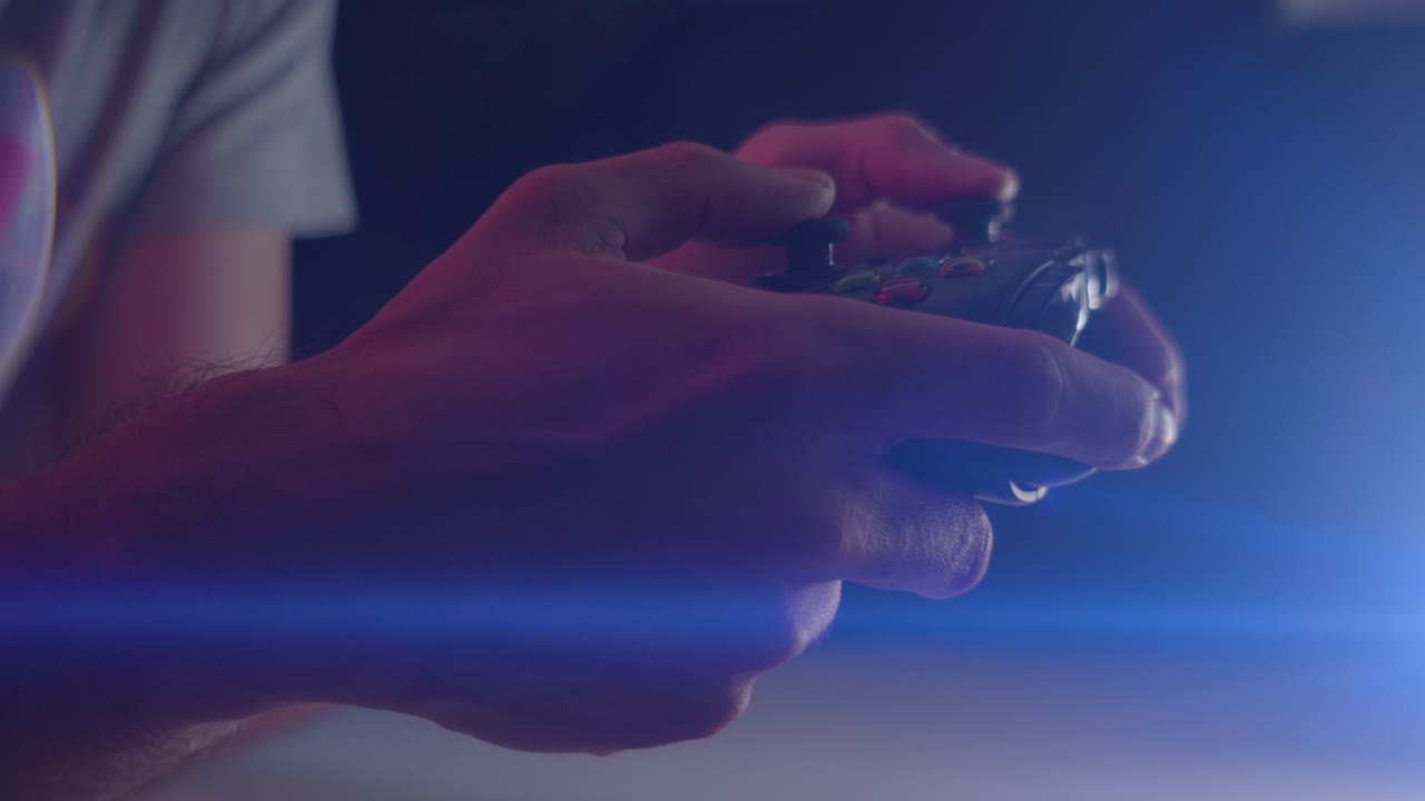 Playing video games in a darkened room with an anamorphic lens flare on a controller buttons playing slowly
