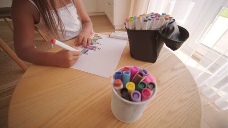 child drawing with markers at a table