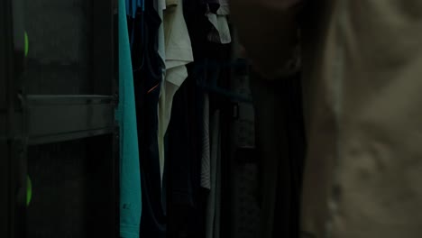 person placing sleeveless shirt on hanger and storing in plastic wardrobe. closeup shot