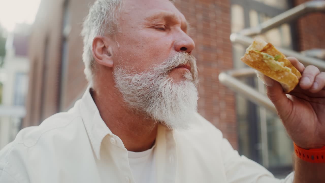 hombre mayor comiendo sándwich al aire libre