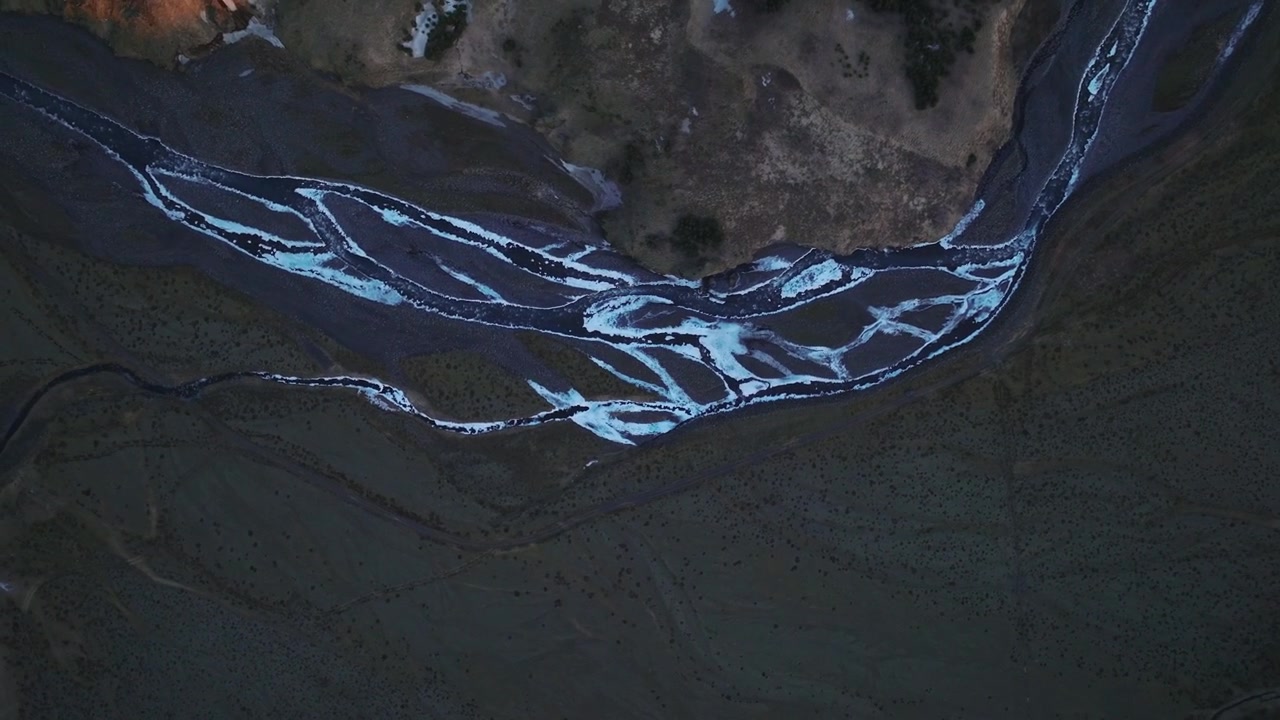 Aerial top view of melting snow rivers flowing down mountains and glacial valleys, in Iceland at sunset