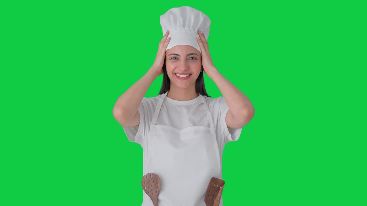 Felice chef professionista indiana che indossa un cappello. Green screen