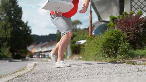 close up: courier trips and falls to asphalt pavement along with a few parcels.