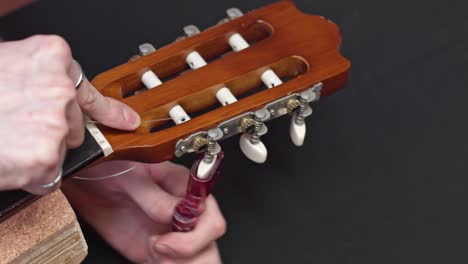 caucasian luthier cleans guitar pegbox takes off strings cut with tool