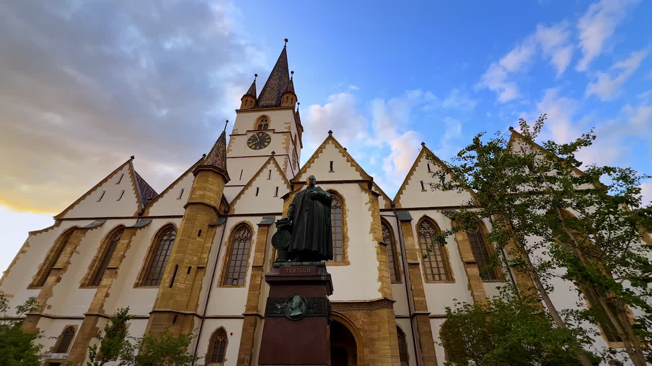 Sibiu, Romania, 17 July 2025: Statue of Bishop Georg Daniel Teutsch, in Sibiu city, Romania. Low angle view. Beautiful building of Lutheran Cathedral of Saint Mary at backdrop
