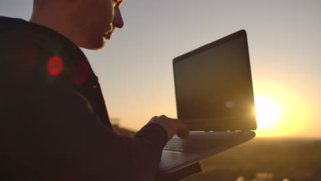 hombre hipster con una computadora portátil en el borde del techo. freelancer en el trabajo. internet móvil inalámbrico. él trabaja en internet.