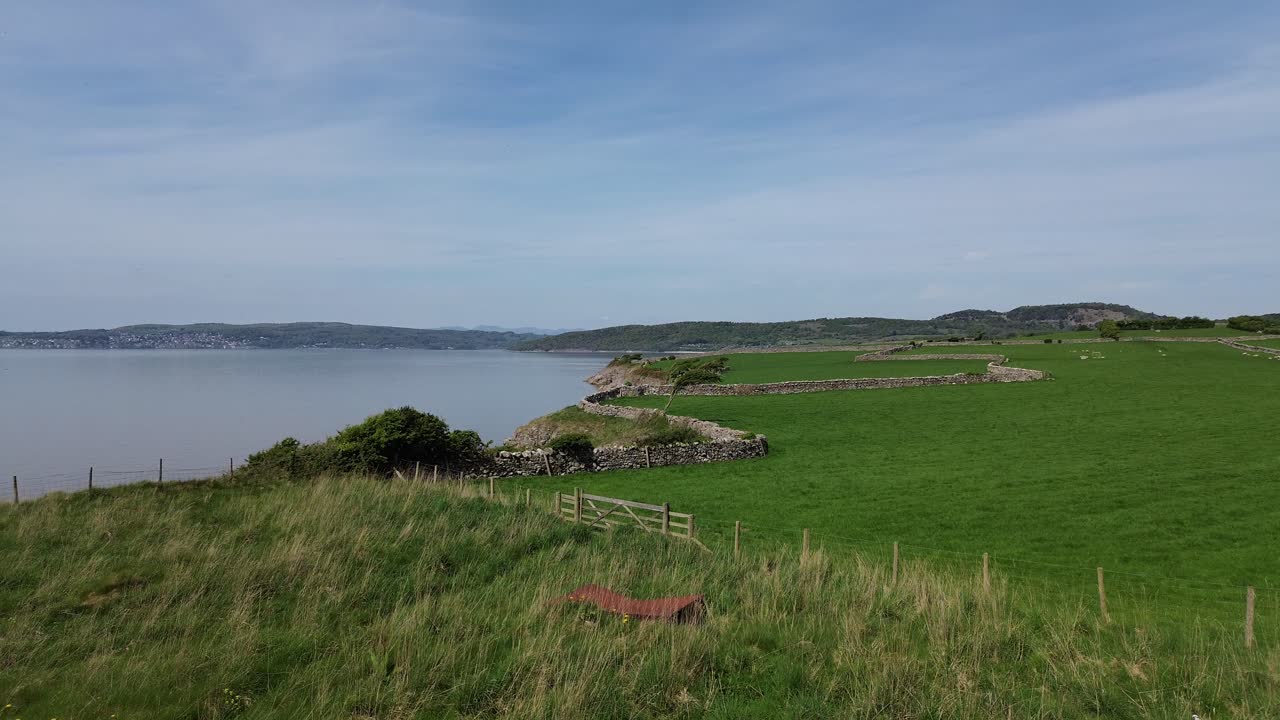 Lake district farming meadow aerial view towards stone wall boundary overlooking Morecambe bay