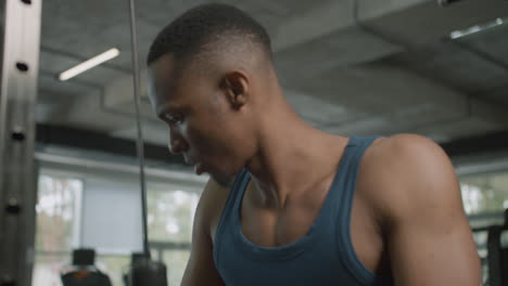 vista de cerca de un hombre afroamericano sosteniendo las manijas de los cables de la máquina de gimnasia