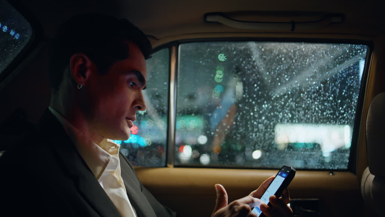 gerente nervioso usando teléfono inteligente en primer plano del coche. hombre mirando gotas de lluvia ventana