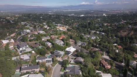 sweeping aerial view of a suburban neighborhood, a wide panorama over trees and homes, with mountains in the background