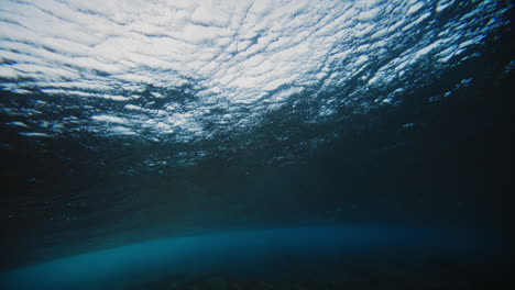 surface of ocean water at cloudbreak fiji gradually turns lighter as wave barrels into vortex underwater