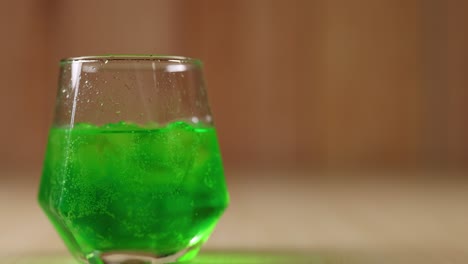 green beverage with ice cubes in glass